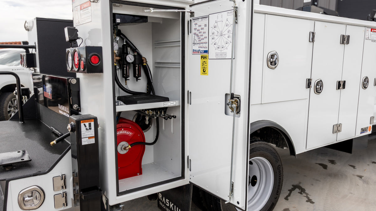 Open compartments on a Raskull service body showing installed air and fluid equipment